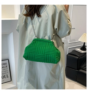 Chic woven clutch bag in vibrant green with silver chain strap shown on beige trench coat
