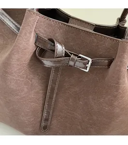 Close-up of dark brown suede tote bag featuring polished silver hardware and leather trim