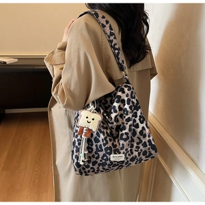 Detailed view of a leopard print tote bag featuring a cute toast plush pendant and label