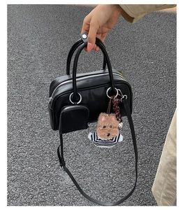 Detail of black leather handbag with a mini zipper pouch and plush dog charm