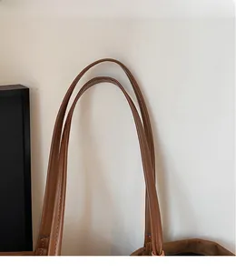 Close-up of smooth brown leather shoulder straps with detailed stitching on tote bag