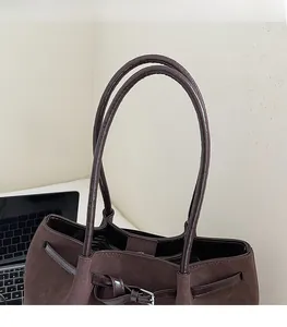 Close-up of vintage brown tote bag with dual shoulder straps and silver metal buckle detail