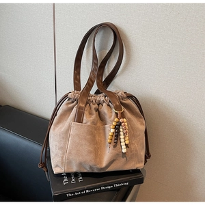 Detail of suede bucket bag featuring ethnic bead tassels and leather shoulder straps