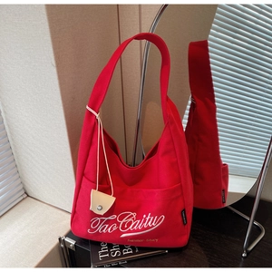 Detail of red canvas tote bag with white embroidery and small card holder charm