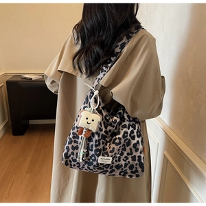 Detail of leopard print canvas bag featuring a cute toast plush pendant and logo patch