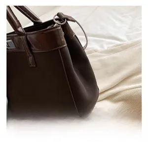 Detail shot of the silver metal clasp on a dark brown leather and canvas tote handbag