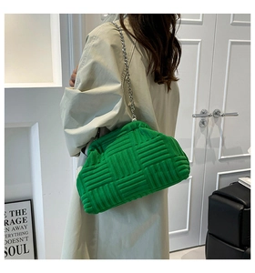 Detalle del bolso de hombro trenzado verde con cadena plateada y textura acolchada