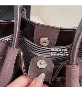 Detail view of the magnetic buckle and striped lining inside the vintage coffee tote bag