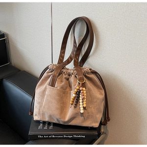 Detail of vintage suede tote bag with leather handles and decorative wooden bead tassel