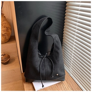 Détail du sac hobo en daim noir avec nœud coulissant et breloque cœur doré