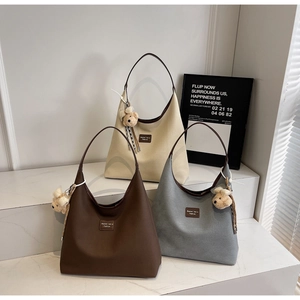 Vue détaillée de grands sacs cabas en toile en marron, beige et gris avec breloque ours