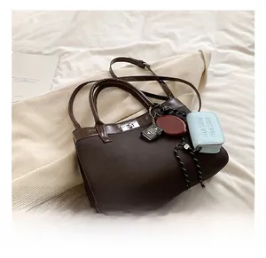 Detail showing the vintage brown tote bag with MASBN charms on soft beige fabric