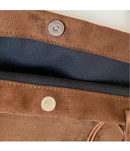 Detail of silver magnetic snap closure on brown faux suede tote bag with black lining