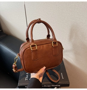 Detailed close-up of brown faux leather vintage bowling bag with gold zipper and strap