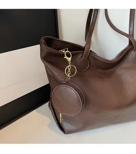 Detail of dark brown tote bag featuring a round zipper coin purse and gold metal hardware
