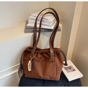 Detail of brown suede tote bag with drawstring closure and ethnic beaded tassel charm
