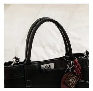 Detail view of black faux leather tote with silver twist lock and mini bible accessory