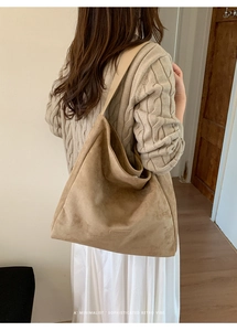 Detail of camel suede tote bag showing soft texture and brand patch logo on a model