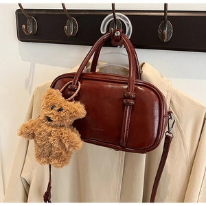Macro shot of retro reddish brown leather bowling bag with cute plush bear keychain