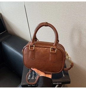 Detail view of a vintage dark brown leather bowling bag placed on a design book