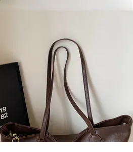 Detail of dark brown tote bag showing litchi grain PU leather and fine stitching on straps
