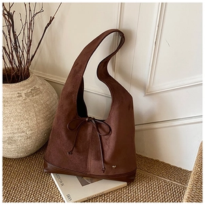 Détail du sac cabas en daim marron foncé avec noeud décoratif et textures rétro chic