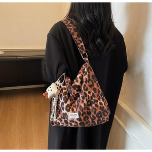 Detailed view of leopard print canvas tote bag with a cute lamb charm and wide shoulder strap