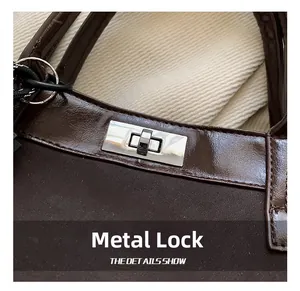 Close-up of elegant metal rectangular lock on deep brown mixed-texture leather shoulder bag