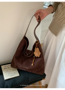 Detail of dark brown suede hobo tote with leather handle and cute plush bear charm