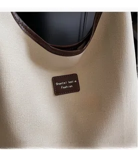 Détail du sac en toile beige avec finitions en cuir marron et écusson décoratif