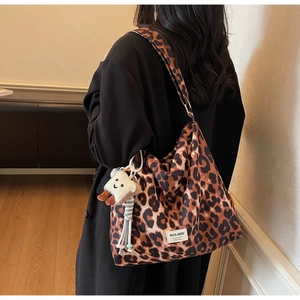 Detail shot of a leopard print tote bag with a plush toast charm on the shoulder strap