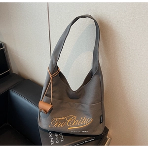 Detail of dark grey canvas tote bag with orange embroidery and leather accessory