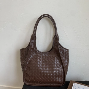 Detail of deep brown woven tote bag featuring premium Intrecciato pattern and dual handles