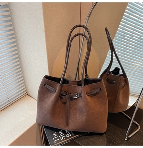 Detail of vintage matte brown tote bag showing textured leather and metallic buckle straps
