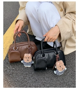Detail showing vintage Boston bags in brown and black with cute bear pendants and front pocket