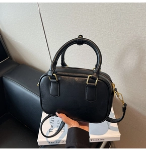 Minimalist black PU leather handbag on books showing smooth matte texture and gold hardware