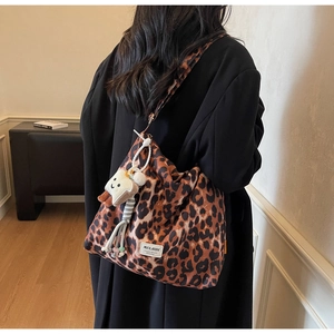 Detail shot of a leopard print canvas tote bag with a plush toast charm on the side