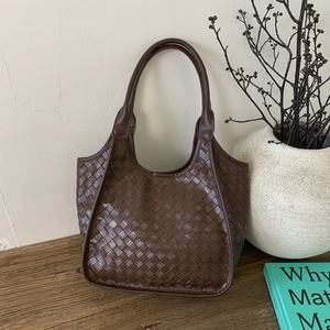 Detail of dark brown hand-woven hobo bag with thick handle in a minimalist setting