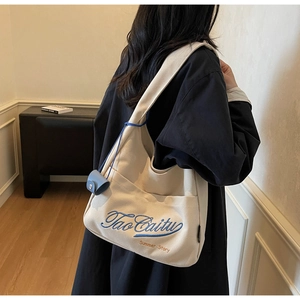 Detail of beige canvas tote bag featuring blue Tao Caitu embroidery and mini pouch