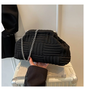 Close-up of black woven cloud clutch bag with delicate silver metal chain strap