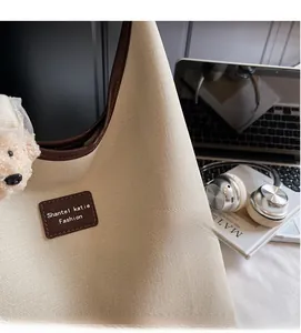Gros plan du sac en toile beige avec finitions en cuir marron et pendentif ours mignon
