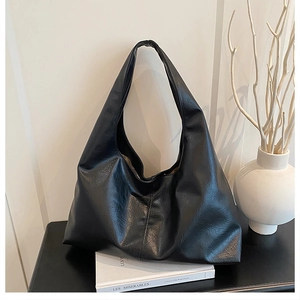 Minimalist black faux leather large tote bag on a desk in a minimalist interior setting