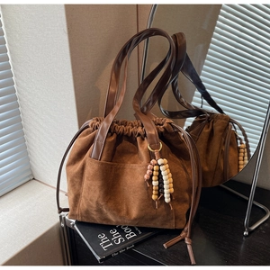 Detail of brown suede bucket bag with leather strap and colorful wooden bead charms