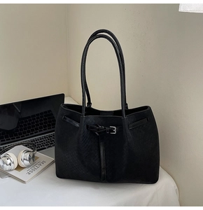 Close-up of black pleated tote bag with woven texture and long shoulder straps