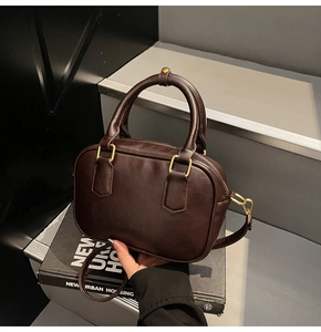 Detail of vintage brown leather handbag on stairs with matte gold hardware accents