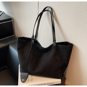 Close-up of minimalist black suede tote bag with smooth matte texture and shoulder straps