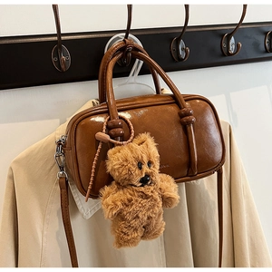 Detail of retro brown leather handbag with plush bear charm hanging on a hanger