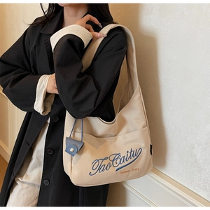Detail of beige canvas tote bag featuring blue embroidery and orange summer story text