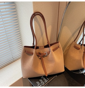 Detail of warm brown woven leather tote bag with silver buckle and vintage texture