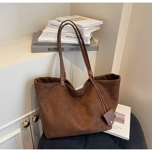 Detailed close-up of brown suede tote bag featuring fine texture and leather charm